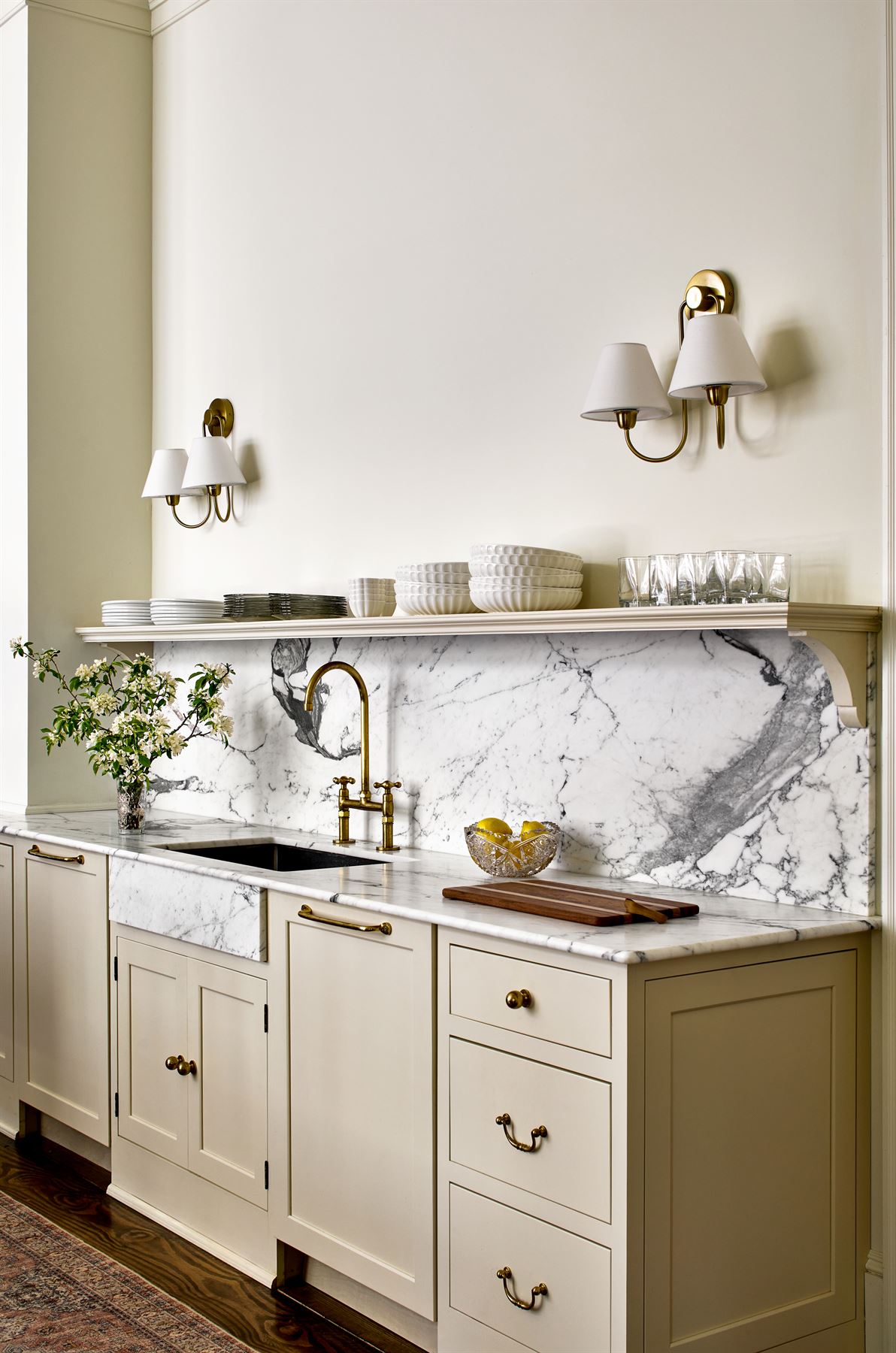 Kitchen wall with marble backsplash, open shelf and brass sconces
