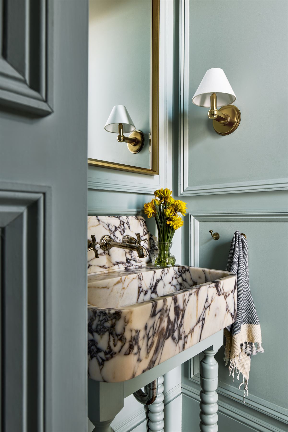 Powder room with paneled walls and a marble console sink